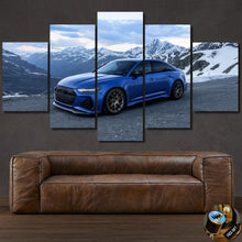 Load image into Gallery viewer, Multi-panel canvas print of blue Audi RS6 C8 Sedan against snowy mountain backdrop above brown leather sofa