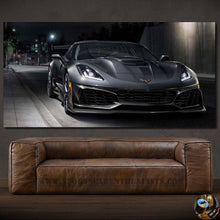 Load image into Gallery viewer, Chevrolet Corvette canvas wall art showing a sleek black sports car parked on a city street at night above a brown leather sofa