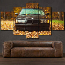 Load image into Gallery viewer, BMW E36 canvas wall art featuring front view of car in autumn setting, multi-panel framed print above brown leather sofa