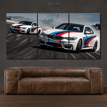 Load image into Gallery viewer, Three-panel canvas wall art of a BMW M4 drifting on a racetrack above a brown leather sofa