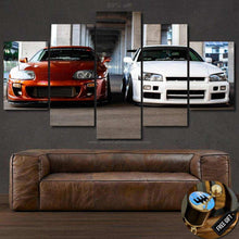 Load image into Gallery viewer, Toyota Supra and Nissan GT-R R34 canvas wall art above brown leather sofa with gift gear shifter keychain