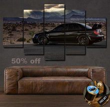 Load image into Gallery viewer, Impreza STI Canvas wall art set featuring a black sports car on a desert road with mountains, displayed above a brown leather sofa