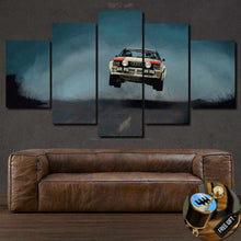 Load image into Gallery viewer, Audi Quattro Canvas wall art featuring a vintage rally car in mid-air over a road, displayed as a five-piece framed canvas set above a brown leather sofa.