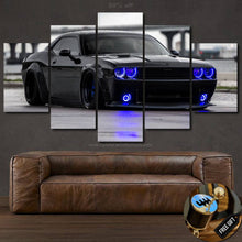 Load image into Gallery viewer, Black Dodge Challenger canvas wall art with blue headlights displayed above brown leather sofa