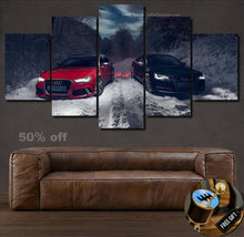 Load image into Gallery viewer, Audi Canvas wall art featuring red and black Audi cars on a snowy forest road displayed above a brown leather sofa with a free gear shifter keychain gift.