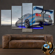 Load image into Gallery viewer, GT-R R34 Skyline blue and silver sports car canvas wall art with neon underglow displayed above brown leather sofa