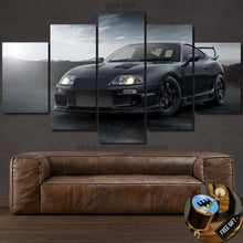 Load image into Gallery viewer, Five-piece canvas wall art featuring a black Toyota Supra MK4 sports car with a mountainous background above a brown leather sofa