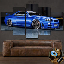 Load image into Gallery viewer, Blue Nissan GT-R R34 Skyline multi-panel canvas wall art above a brown leather sofa with free gear shifter keychain gift shown
