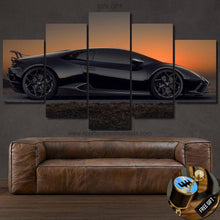 Load image into Gallery viewer, Multi-panel canvas print of black Lamborghini Huracan sports car at sunset displayed above brown leather sofa