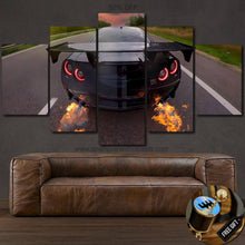 Load image into Gallery viewer, Nissan GT-R R35 canvas wall art with rear view of car flaming exhaust and illuminated tail lights displayed above brown leather sofa