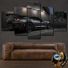 Load image into Gallery viewer, Chevrolet Corvette wallpaper canvas print showing a black sports car at night, displayed above a brown leather sofa.