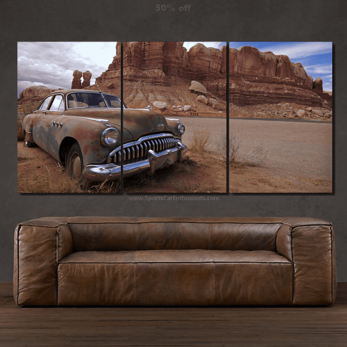 Three-piece Buick Canvas wall art featuring a vintage car in a desert landscape above a brown leather sofa.