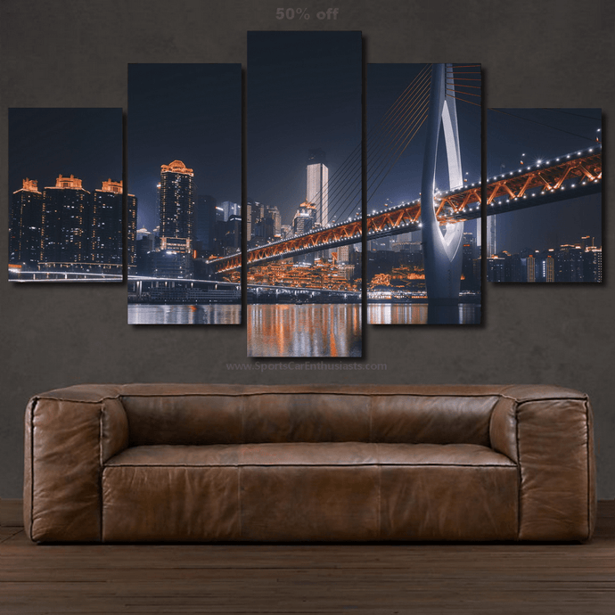 5-piece framed canvas wall art of illuminated city skyline and bridge at night above brown leather sofa