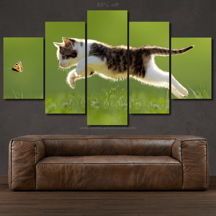 Canvas 5pcs wall art featuring a jumping cat and butterfly over green grass above a brown leather sofa